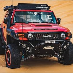 a red and black four door truck driving through the desert