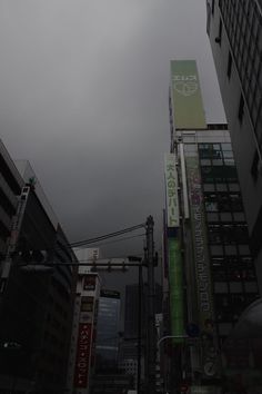 a city street with tall buildings on both sides and signs in the sky above them