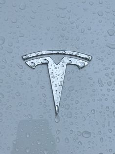 the tesla logo is shown on a car's windshield with water droplets around it