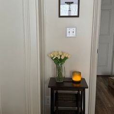 a vase with flowers and a candle on a small table in front of the door