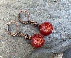 Cute copper earrings with small red and gold hibiscus flower beads. Vintage Red Copper Earrings, Red Copper Earrings, Nickel-free Red Copper Earrings, Red Copper Drop Earrings, Red Dangle Earrings With Flower Charm, Red Copper Dangle Earrings, Adjustable Nickel-free Red Flower Earrings, Red Copper Earrings Gift, Red Copper Earrings As Gift