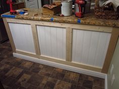 a kitchen counter that is being constructed with wood paneling and white paint on it