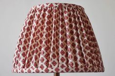 a lamp with a red and white pattern on it's fabric shade is sitting on a wooden table