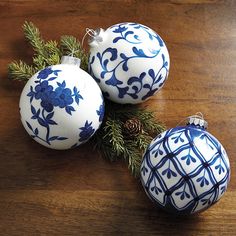 three blue and white ornaments sitting on top of a wooden table