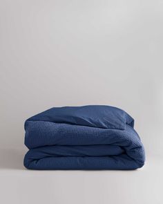 two blue sheets folded on top of each other in front of a white wall and floor