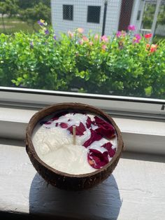 a bowl filled with food sitting on top of a window sill next to flowers