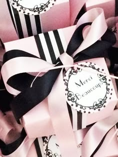 pink and black gift boxes with ribbons tied around the top one has a name tag on it