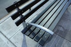 a metal bench sitting on the side of a street next to a sidewalk with no people