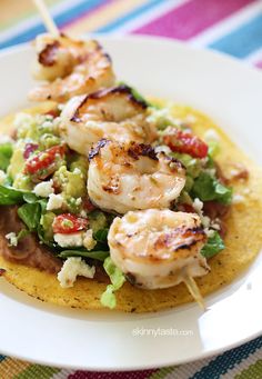 a white plate topped with shrimp and lettuce on top of a tortilla