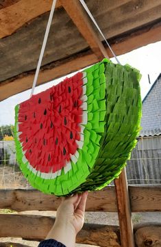 a person holding up a piece of paper that looks like a watermelon