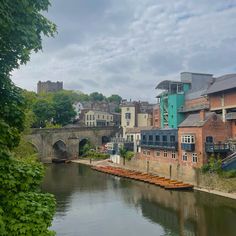 a river running through a city with buildings on both sides and a bridge in the background