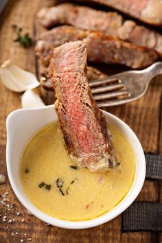 a piece of meat is in a small bowl with some sauce on the table next to it