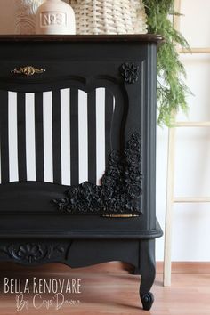 an old piano painted black and white with flowers on the top, sitting in front of a potted plant