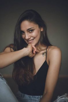 a young woman is smiling and posing for the camera with her hands on her chest