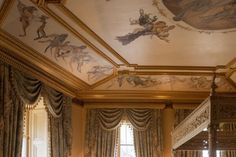 an ornate bedroom decorated in gold and white with paintings on the walls, ceiling and bed