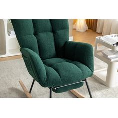 a green rocking chair sitting on top of a white rug next to a coffee table