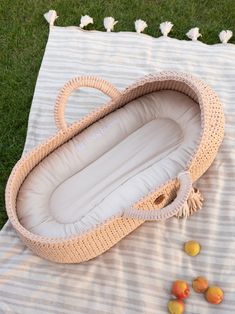 an empty wicker basket sitting on top of a blanket next to some peaches