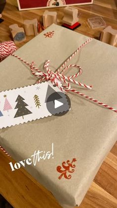 a present wrapped in brown paper with red and white twine on it, tied up to a wooden table