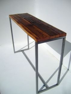 a wooden table sitting on top of a white floor next to a metal frame wall