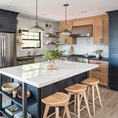 a kitchen island with stools in front of it next to an oven and refrigerator