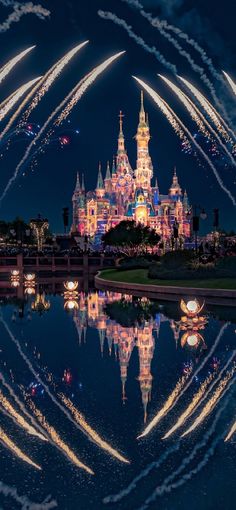 fireworks are lit up in the sky above a castle at night with reflection on water