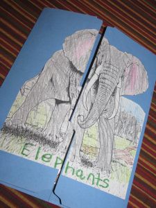 two children's drawings of elephants on blue paper with the word elephants written in green