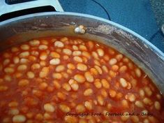 a pot filled with beans sitting on top of a stove next to a burner