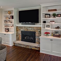 a living room with white shelves and a flat screen tv mounted above the fire place