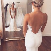 the back of a woman's wedding dress in front of a mirror with her reflection