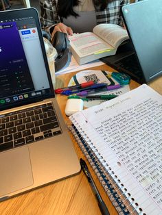 an open laptop computer sitting on top of a wooden desk next to a notebook and pen