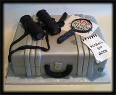 a cake made to look like a suitcase with binoculars on top and stickers around it