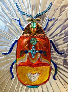 a colorful glass bug sitting on top of a white table next to a silver wall