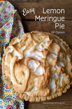 an easy lemon meringue pie is shown on a wooden table with a colorful napkin