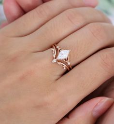 a woman's hand with a diamond ring on top of her finger and the other hand holding an engagement ring