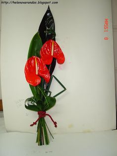 a bouquet of red flowers sitting on top of a white table next to a wall