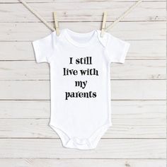 Funny I still live with my parents infant bodysuit Family Matching Onesie With Funny Text For Birthday, Family Matching Birthday Onesie With Funny Text, Birthday Onesie With Funny Text, Cute Fitted Pre-shrunk Onesie, Cute Fitted Onesie With Funny Print, Cute Cotton Onesie, Funny Text Cotton Onesie For Birthday, White Onesie With Funny Text For Birthday, Birthday Onesie With Funny Text In Cotton