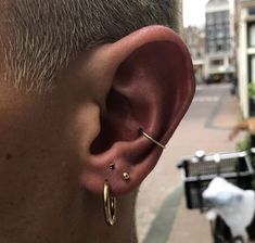 a close up of a person's ear with two small gold hoops on it