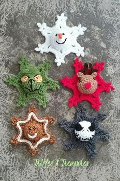 four crocheted snowflakes are sitting on the ground with their faces made to look like animals