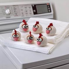 five stuffed chickens sitting on top of a dryer next to a stack of towels