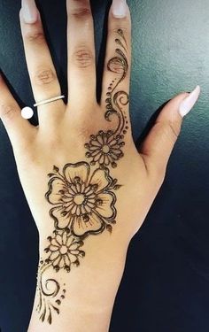 a woman's hand with hennap on it and an intricate flower design