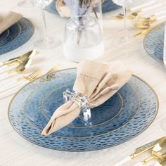 the table is set with blue plates and gold cutlery, silverware, and flowers