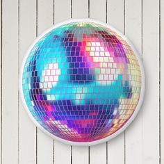 a colorful disco ball hanging from the side of a white wall with wood planks