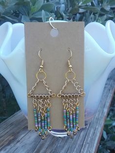 Handcrafted chandelier earrings created with gold chain pieces of varying lengths and a colorful array of seed beads. Multicolor Dangling Beaded Brass Earrings, Multicolor Metal Dangle Chandelier Earrings, Bohemian Gold Beaded Chain Earrings, Multicolor Brass Dangle Beaded Earrings, Multicolor Dangle Beaded Brass Earrings, Gold Beaded Dangle Chandelier Earrings, Bohemian Gold Chandelier Earrings With Colorful Beads, Bohemian Beaded Chain Dangle Chandelier Earrings, Bohemian Beaded Chandelier Dangle Earrings