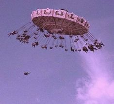 an amusement park ride flying through the air with people on it's sides and in the sky