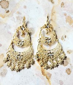 Beautiful traditional Mexican dangling earrings with 14k gold plated and small shiny imitation stones. These beautiful dangling earrings are the ideal gift for any occasion, they can be combined with any outfit both day and night, you will surely look beautiful because they will enhance your beauty making you look distinguished. Features/ Product info -The Main Material: Brass (14k Gold Plated) -Color: Gold - Earrings: 2.83 in (7.2 cm.) (H) 1.33 (W) (3.4 cm) -Earrings weight: (7 grams) Jewelry Love: Your Essential Guide to Caring for Your Treasures -Avoid tangles and snags by handling with care. -Store in a dry, cool place, away from sunlight to prevent damage. Take care to keep it flat to avoid any deformation.  -Put on after applying makeup and perfume. Also, make sure that any creams, b Silver Dangle Clip-on Earrings Gold Plated, Gold-tone Metal Earrings For Wedding, Gold Metal Drop Bridal Earrings, Gold Plated Dangle Chandelier Earrings For Festive Occasions, Gold-plated Dangle Chandelier Earrings For Festive Occasions, Yellow Gold Metal Earrings For Festive Occasions, Gold Plated Dangle Flower Earrings, Gold-plated Dangle Flower Earrings For Pierced Ears, Gold Plated Flower Dangle Earrings