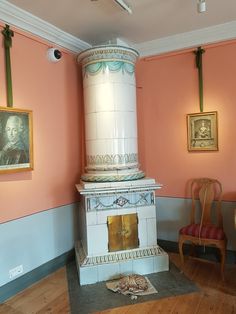 a room with pink walls and paintings on the wall next to a white fire place