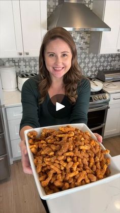 a woman holding up a large white bowl filled with fried food in her hands and smiling at the camera