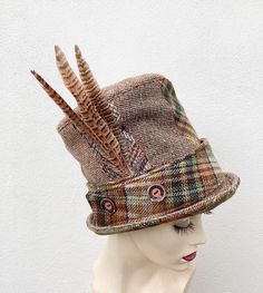 This unusual tall top hat has an 8 section crown made from various recycled tweed and wool fabrics making it a sustainable fashion choice. The removable band with button detailing has brown velvet on one side and tweed on the other for an alternate look. The feather brooch is also removable. * Size M/L to fit headsize 58cms/22.83inches * Crown height 19cms/7.48inches * Dryclean only To see more of my hats please click https://www.etsy.com/uk/shop/OverToYou I design, pattern cut and create all my Unusual Hats, Sewing Hats, Feather Brooch, Tweed Top, Crown Heights, Wool Top, Top Hats, Brown Velvet, Love Hat