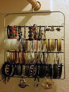 a rack with bracelets and rings hanging from it's sides on a wall