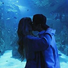 a man and woman kissing in front of an aquarium